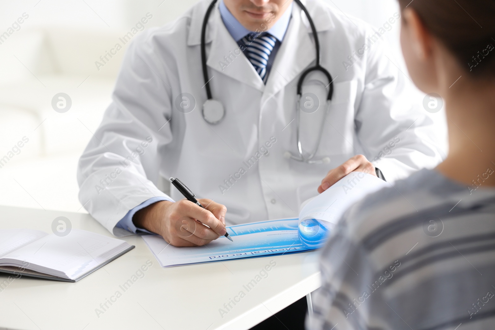 Photo of Doctor consulting patient at desk in clinic, closeup