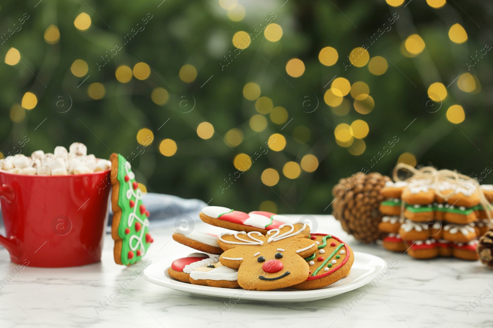 Photo of Decorated cookies and hot drink on white marble table against blurred Christmas lights