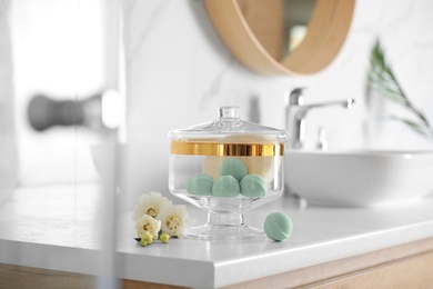 Photo of Jar with bath bombs and bath sponge on white countertop indoors