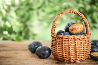 Photo of Delicious ripe plums on wooden table against blurred background. Space for text