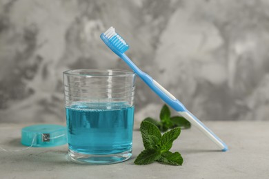 Photo of Mouthwash, toothbrush and dental floss on grey table