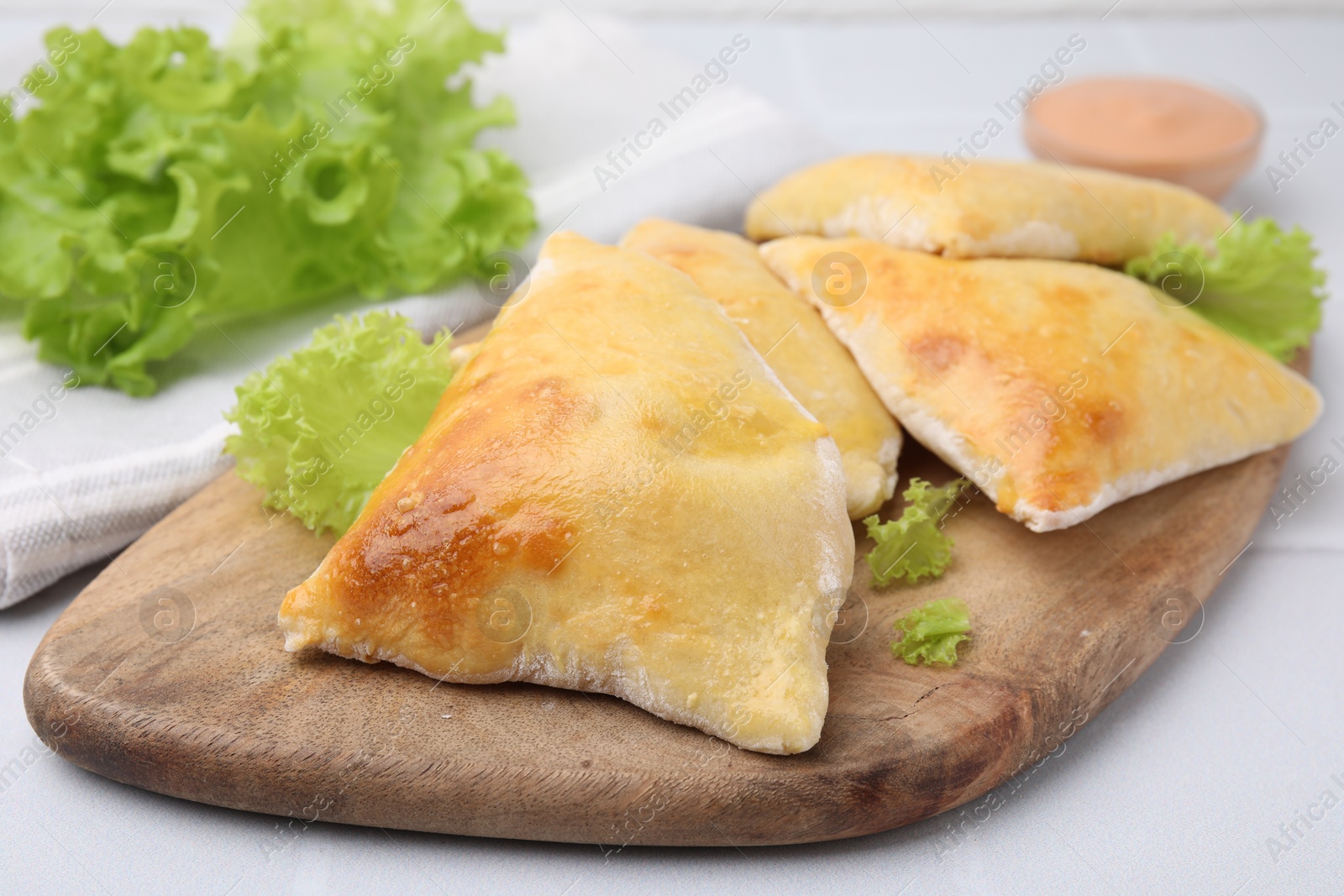 Photo of Delicious samosas and lettuce on white table, closeup