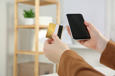 Online payment. Woman using credit card and smartphone indoors, closeup. Space for text