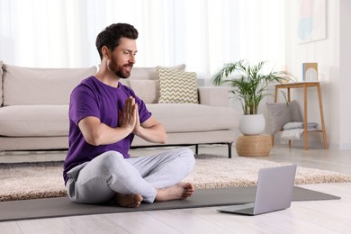 Photo of Man meditating near laptop at home, space for text