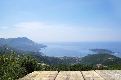 Image of Empty wooden surface and view of beautiful mountains and sea on sunny day