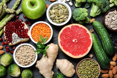 Fresh vegetables, fruits and seeds on black table, flat lay