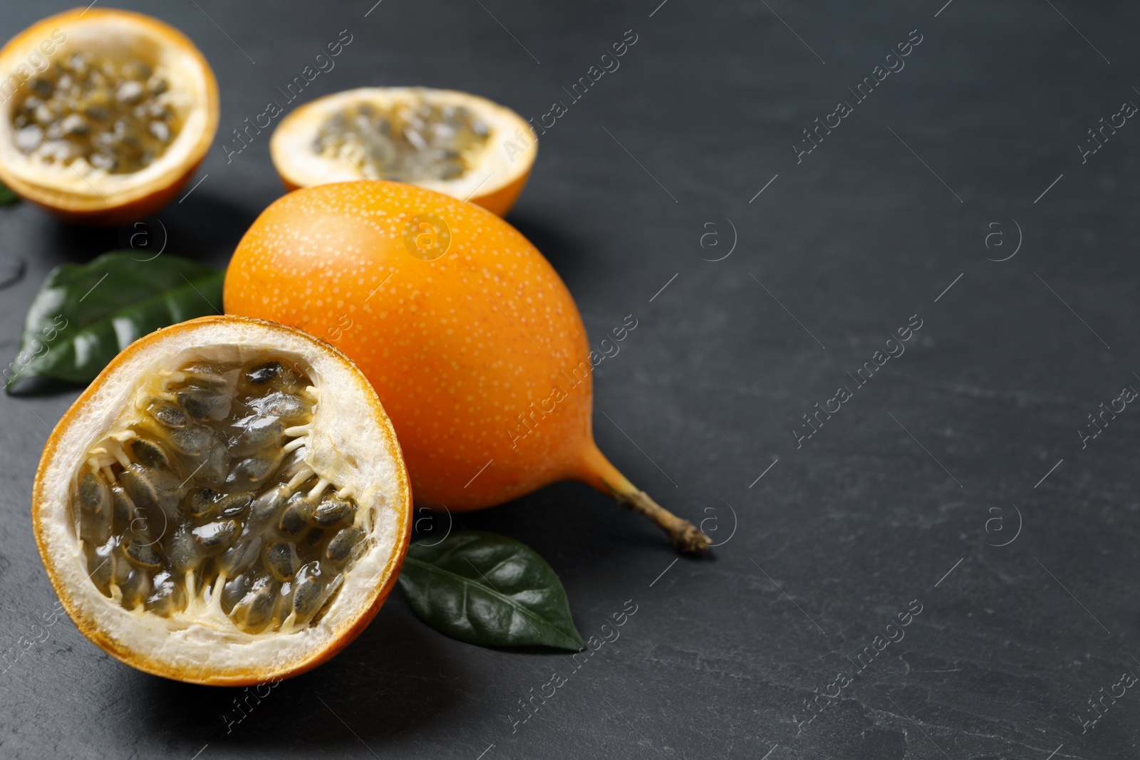 Photo of Delicious ripe granadillas on black table. Space for text