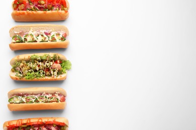 Delicious hot dogs with different toppings on white background, flat lay. Space for text
