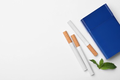 Photo of Menthol cigarettes, pack and mint on white background, flat lay. Space for text