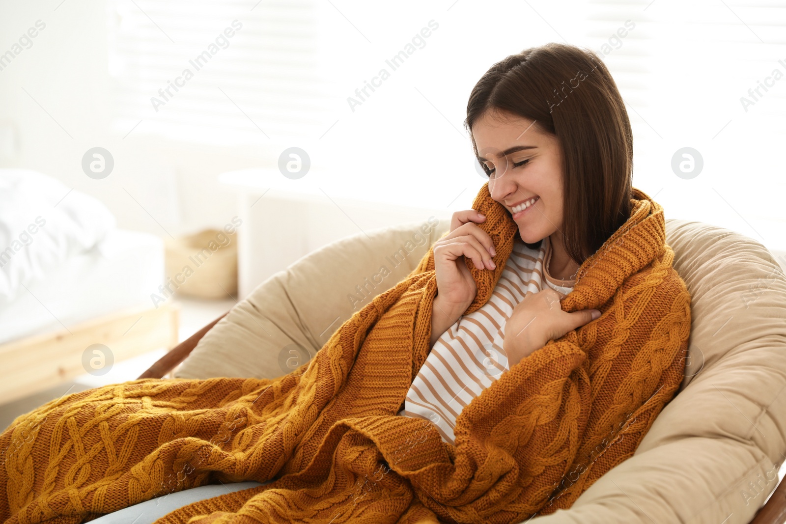 Photo of Woman covered with warm orange plaid sitting at home