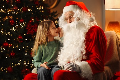 Photo of Merry Christmas. Little girl whispering her wish to Santa at home, space for text
