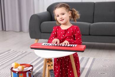 Photo of Little girl playing toy piano at home