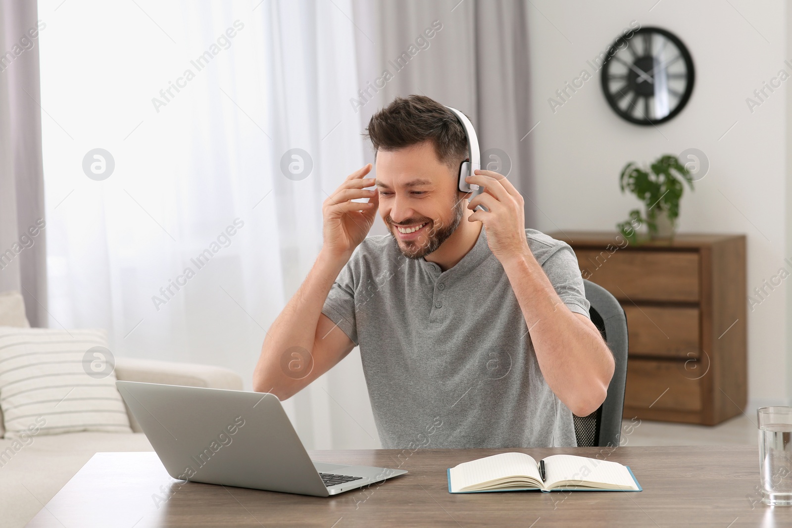 Photo of Man in headphones studying on laptop at home. Online translation course