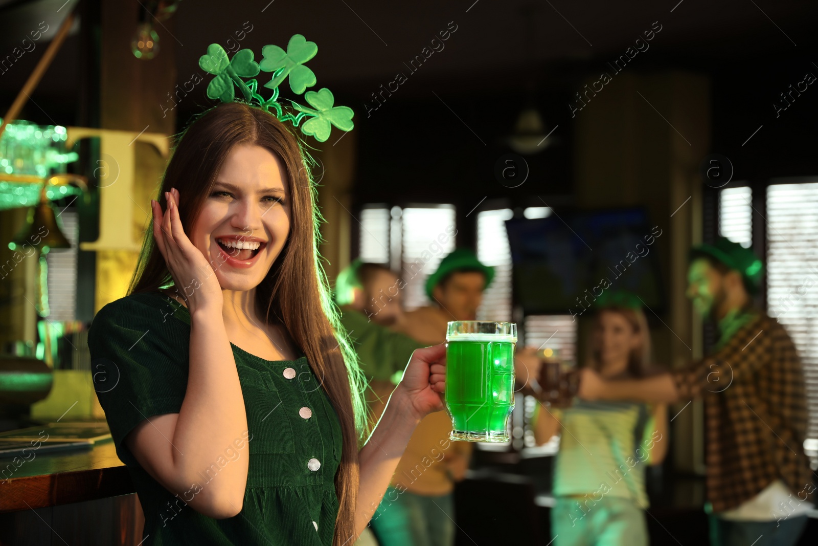 Photo of Young woman with glass of green beer in pub. St. Patrick's Day celebration