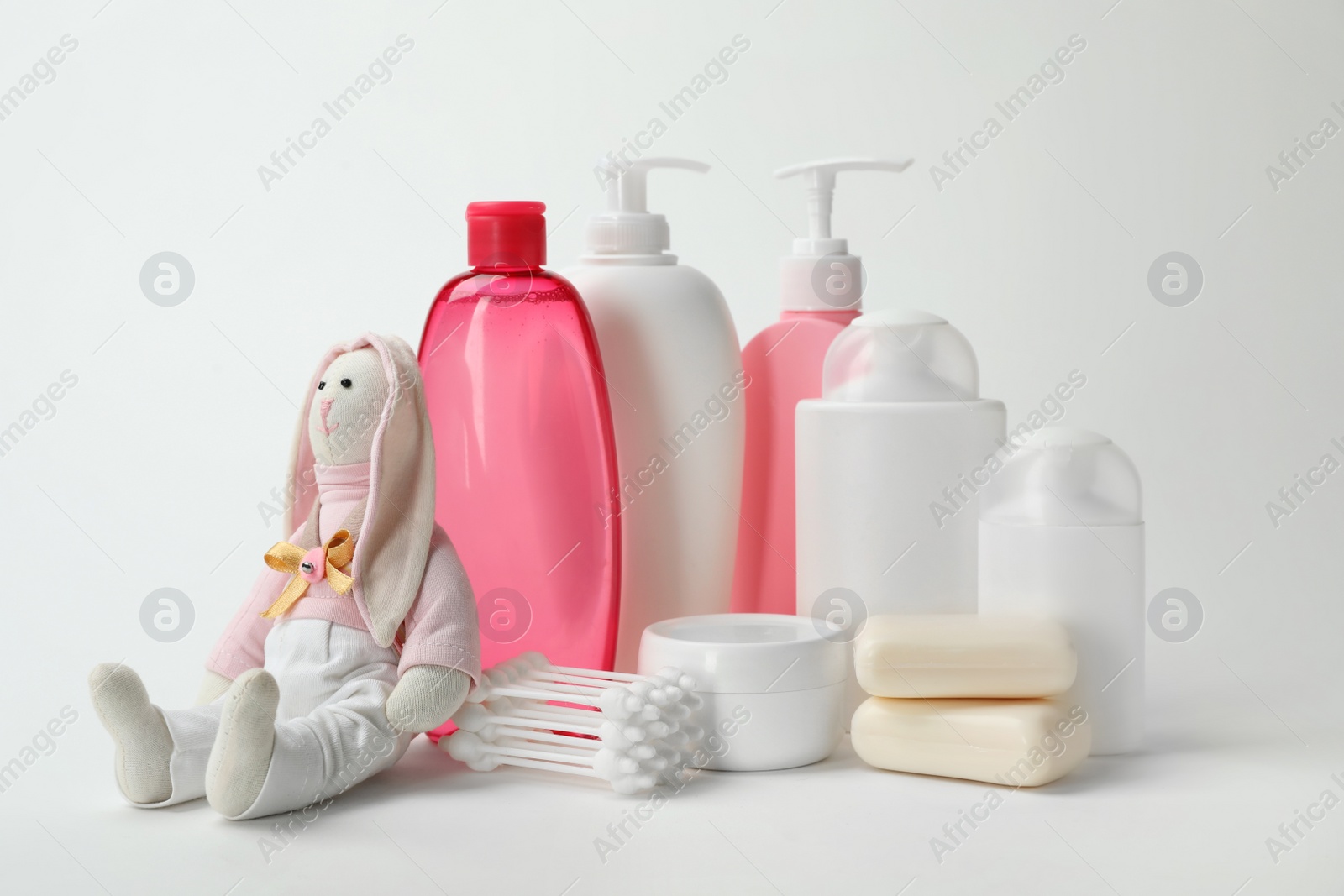 Photo of Baby cosmetic products, toy and cotton swabs on white background