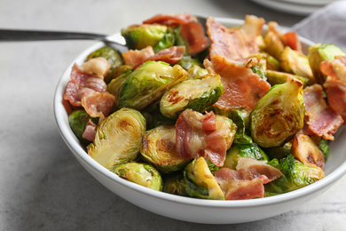 Photo of Delicious roasted Brussels sprouts with bacon served in bowl, closeup