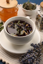 Photo of Aromatic tea with different dry herbs and honey on table, closeup