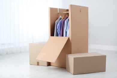 Photo of Wardrobe box with clothes on hangers indoors