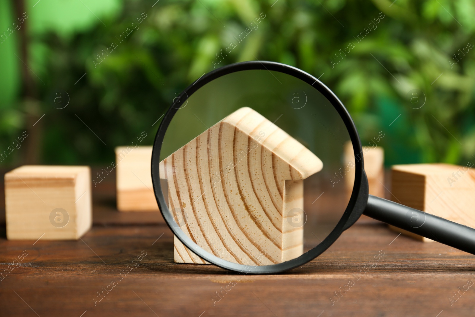 Photo of House model and magnifying glass on wooden table. Search concept