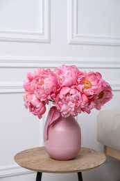 Beautiful bouquet of pink peonies in vase on wooden table indoors