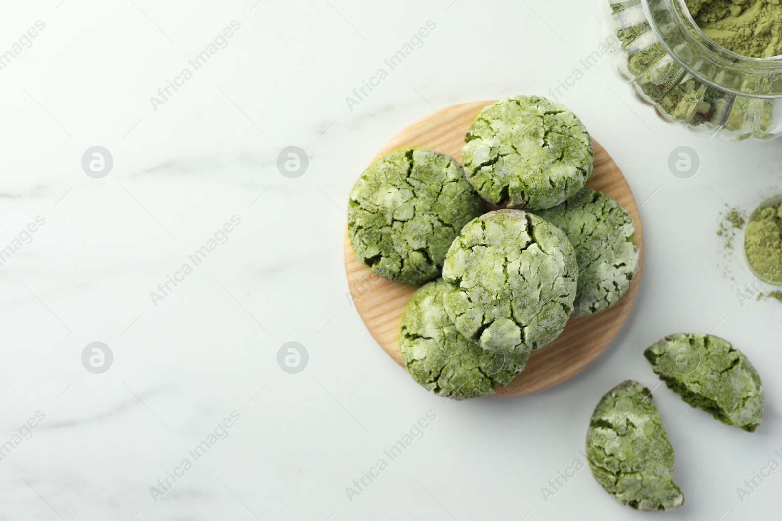 Photo of Board with tasty matcha cookies and powder on white marble table, flat lay. Space for text