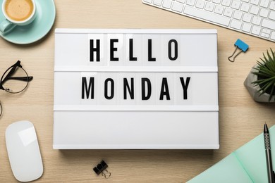 Flat lay composition of lightbox with phrase Hello Monday at workplace