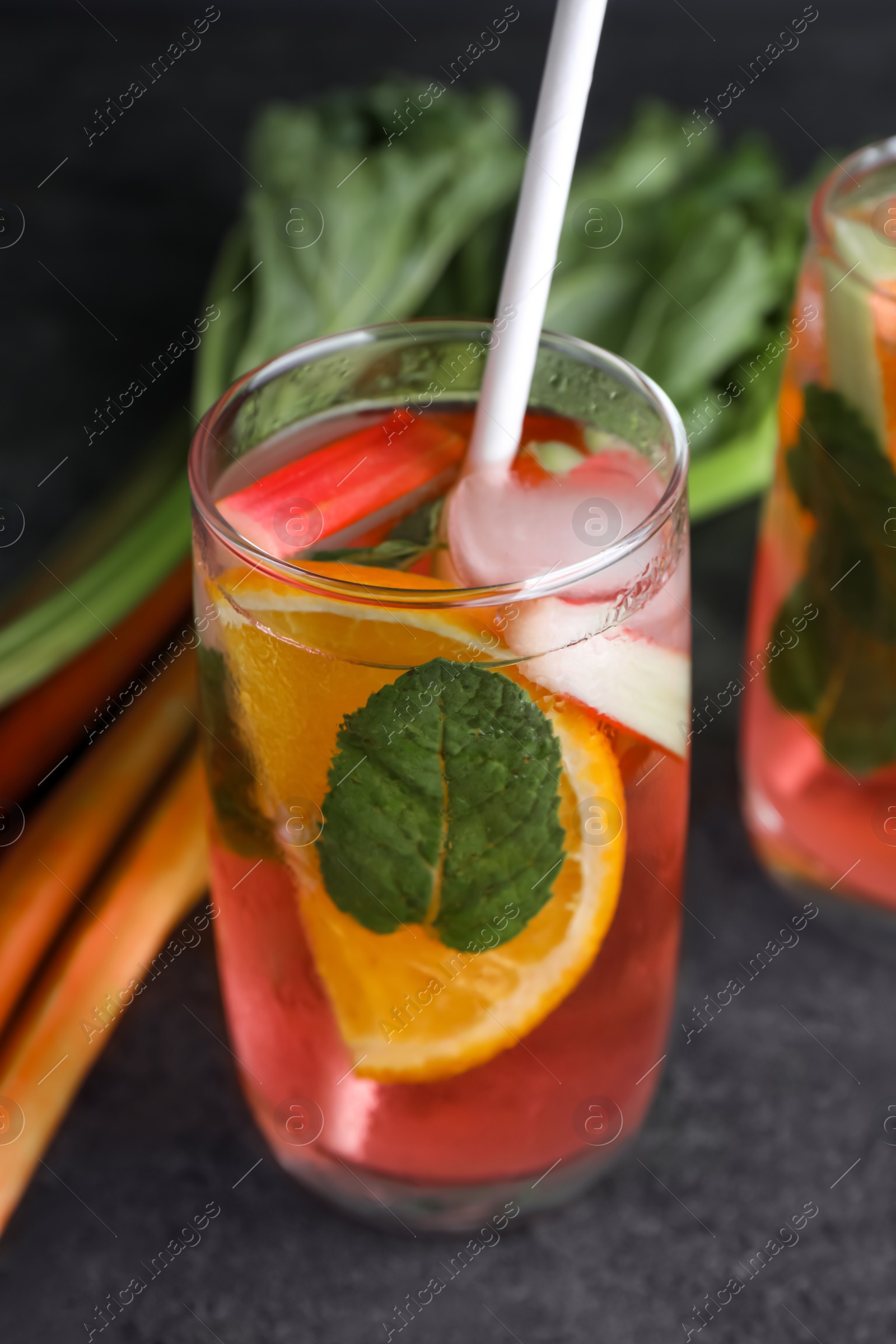 Photo of Glass of tasty rhubarb cocktail with lemon on grey table, closeup