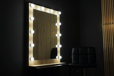 Beautiful mirror with light bulbs and chair in makeup room