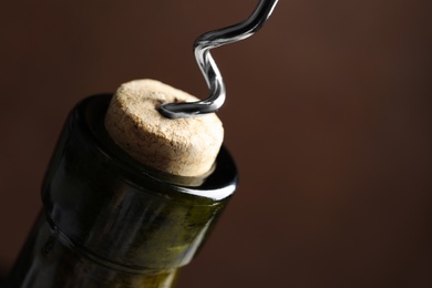 Photo of Opening wine bottle with corkscrew on color background, closeup. Space for text