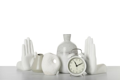 Different stylish vases, alarm clock and other decor elements on table against white background