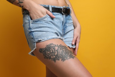 Photo of Woman with tattoos on body against yellow background, closeup