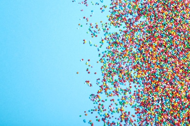 Photo of Colorful sprinkles on light blue background, flat lay with space for text. Confectionery decor