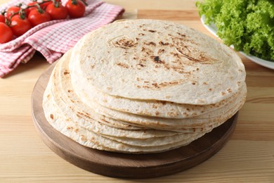 Many tasty homemade tortillas and products on wooden table, closeup