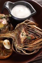 Photo of Tasty grilled artichoke on table, closeup view