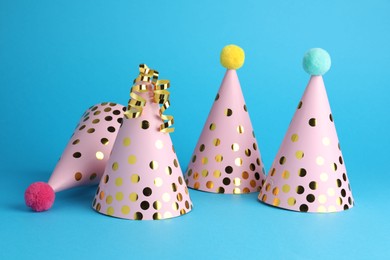 Photo of Pink party hats and serpentine streamers on light blue background