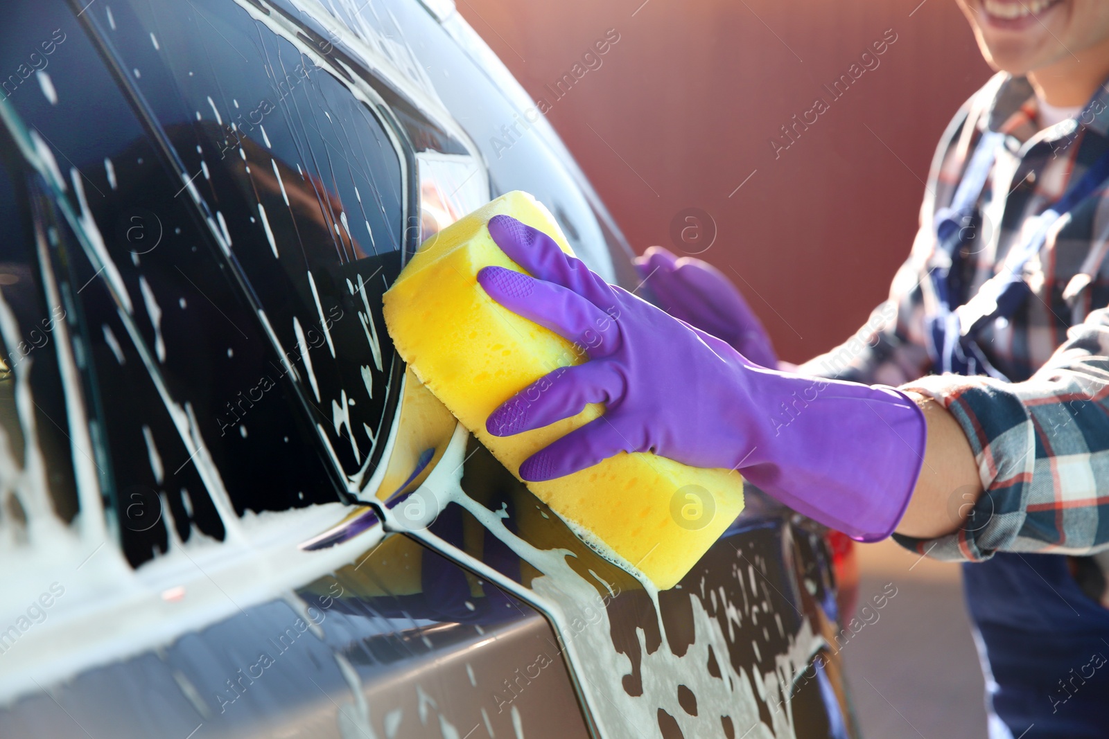 Photo of Worker cleaning automobile with sponge at car wash