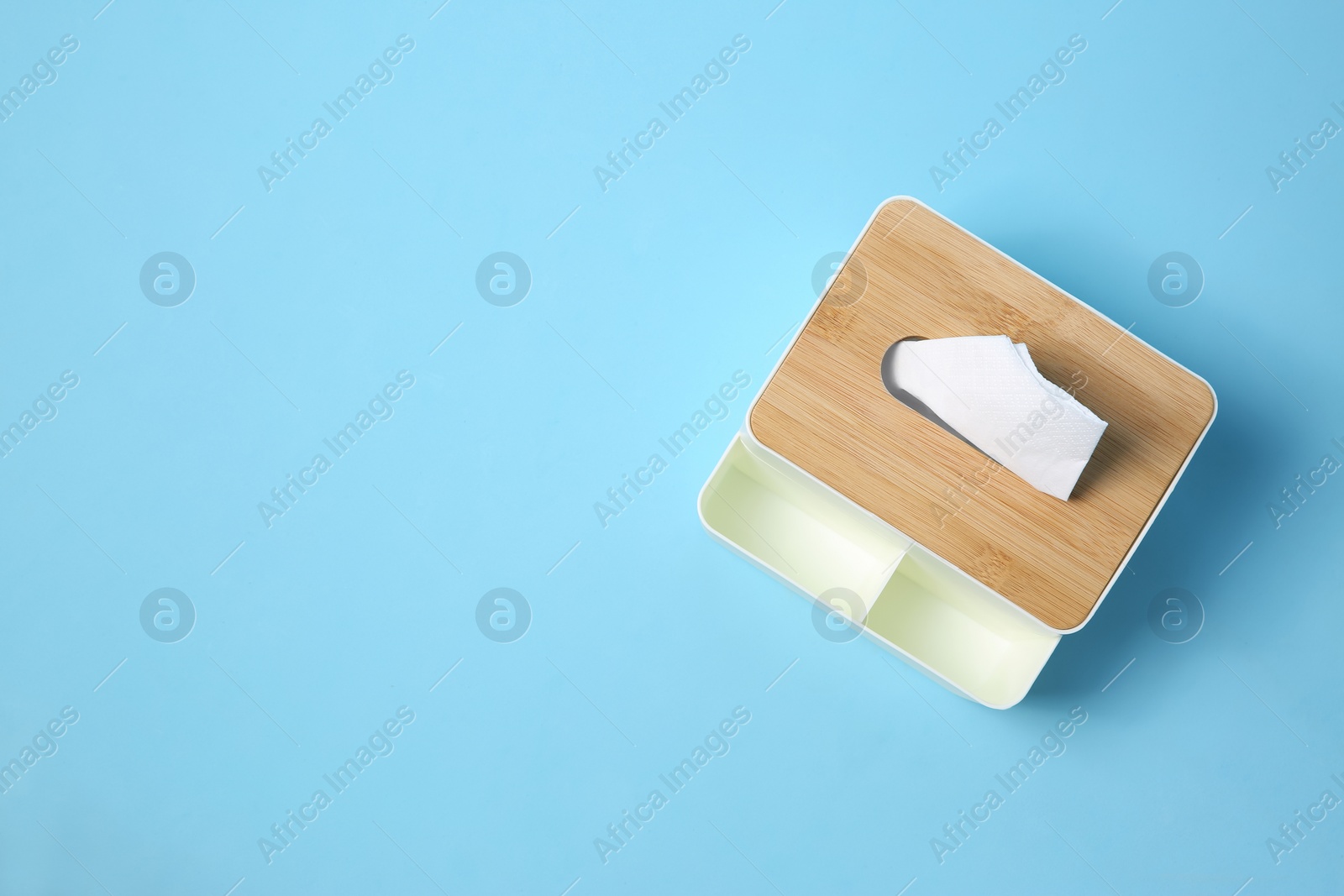 Photo of Holder with paper tissues on light blue background, top view. Space for text