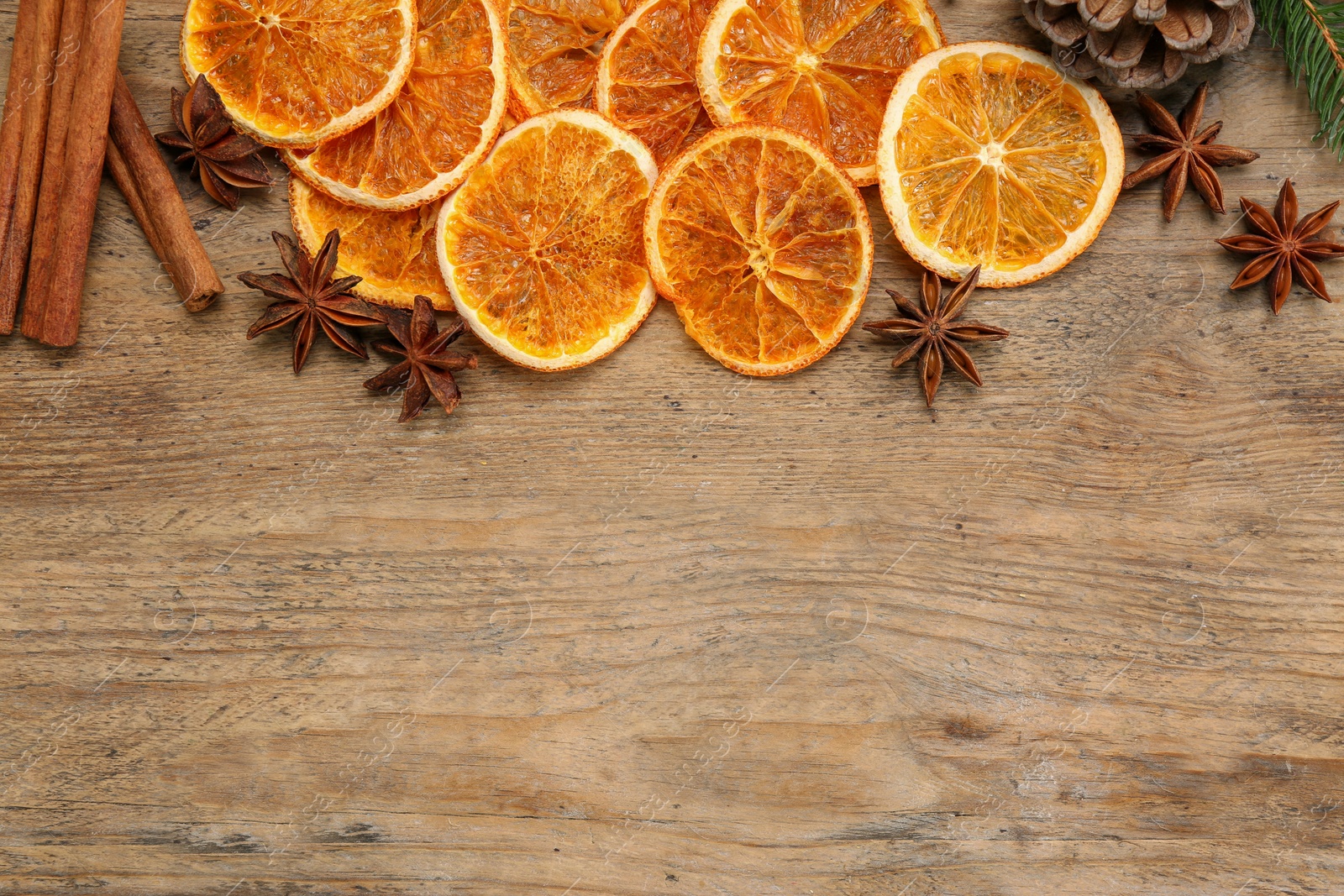 Photo of Dry orange slices, cinnamon sticks and anise stars on wooden table, flat lay with space for text