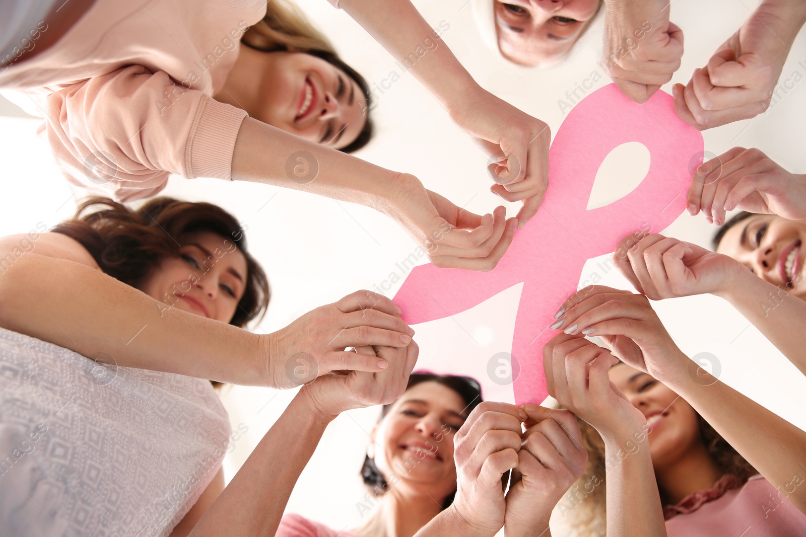 Photo of Women holding pink paper ribbon, bottom view. Breast cancer awareness concept
