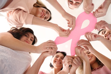 Women holding pink paper ribbon, bottom view. Breast cancer awareness concept