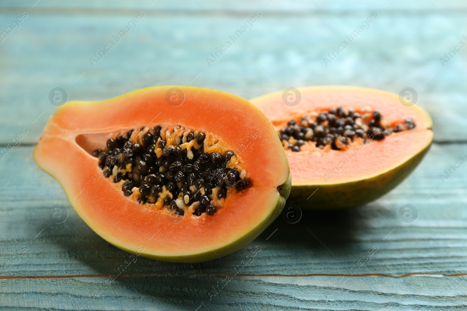 Photo of Fresh halved papaya fruit on wooden table, closeup