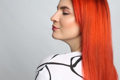 Young woman with bright dyed hair on grey background, closeup