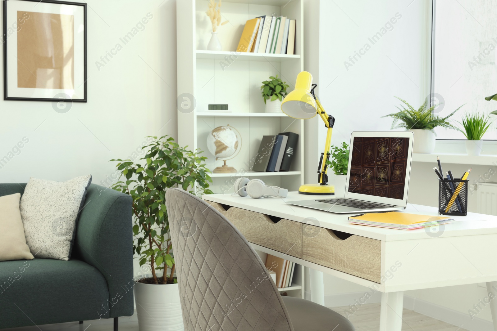 Photo of Cozy workspace with modern laptop on white wooden desk and comfortable chair at home