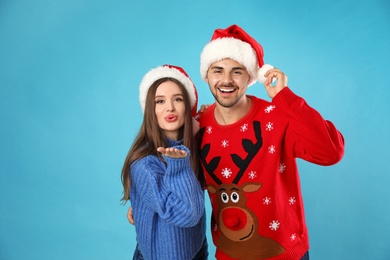 Photo of Couple wearing Christmas sweaters and Santa hats on blue background