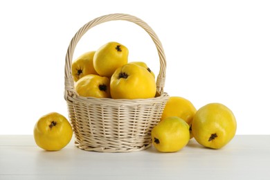 Photo of Basket with delicious fresh ripe quinces on light wooden table against white background