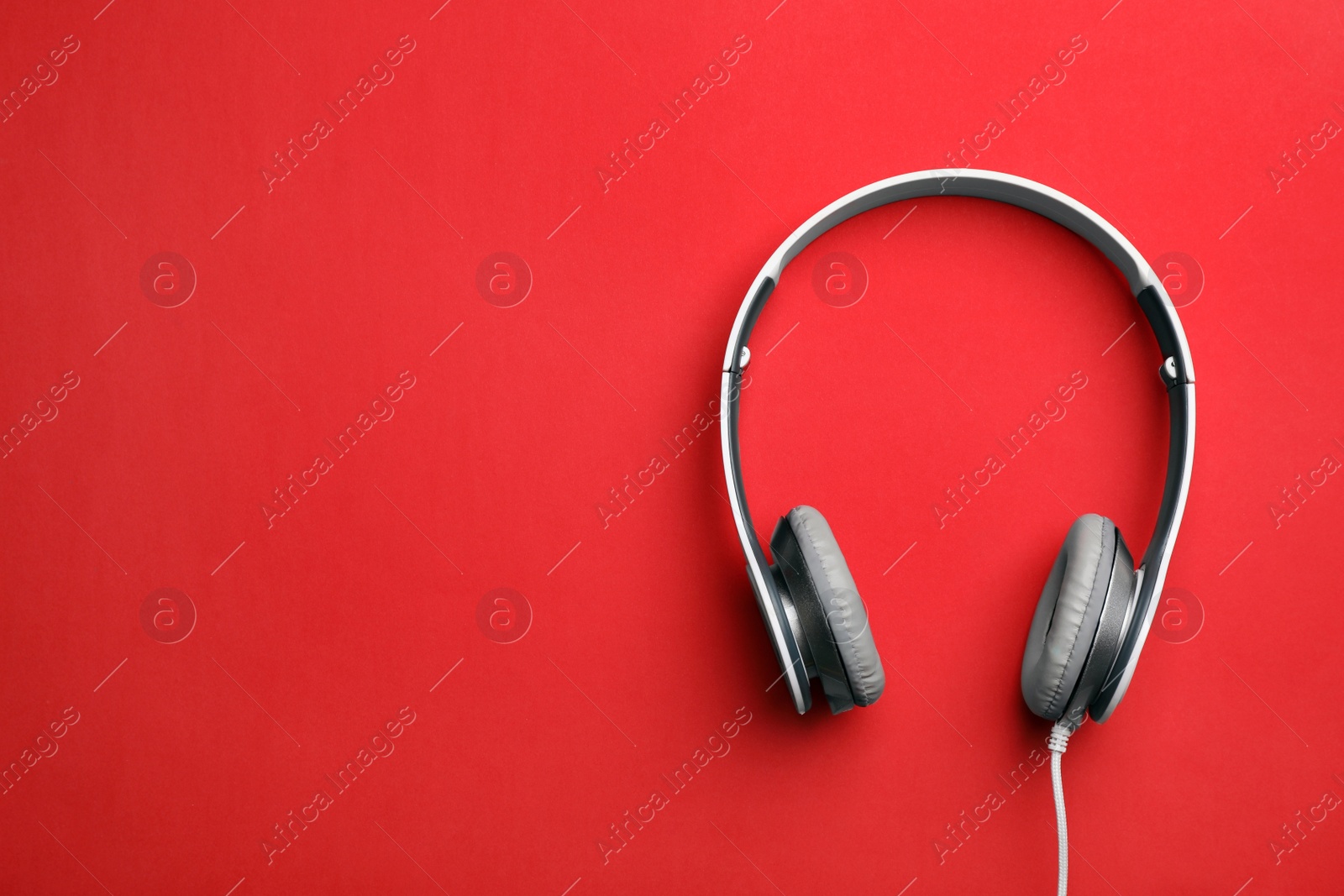 Photo of Stylish modern headphones with earmuffs on color background, top view. Space for text