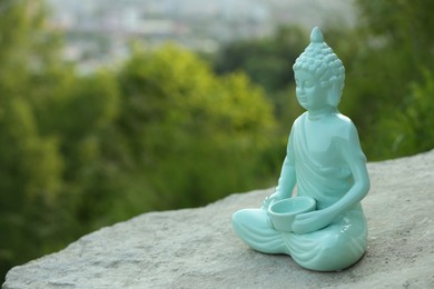 Photo of Decorative Buddha statue on stone outdoors, space for text