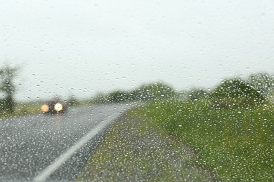 Photo of Blurred view of country road through wet car window. Rainy weather