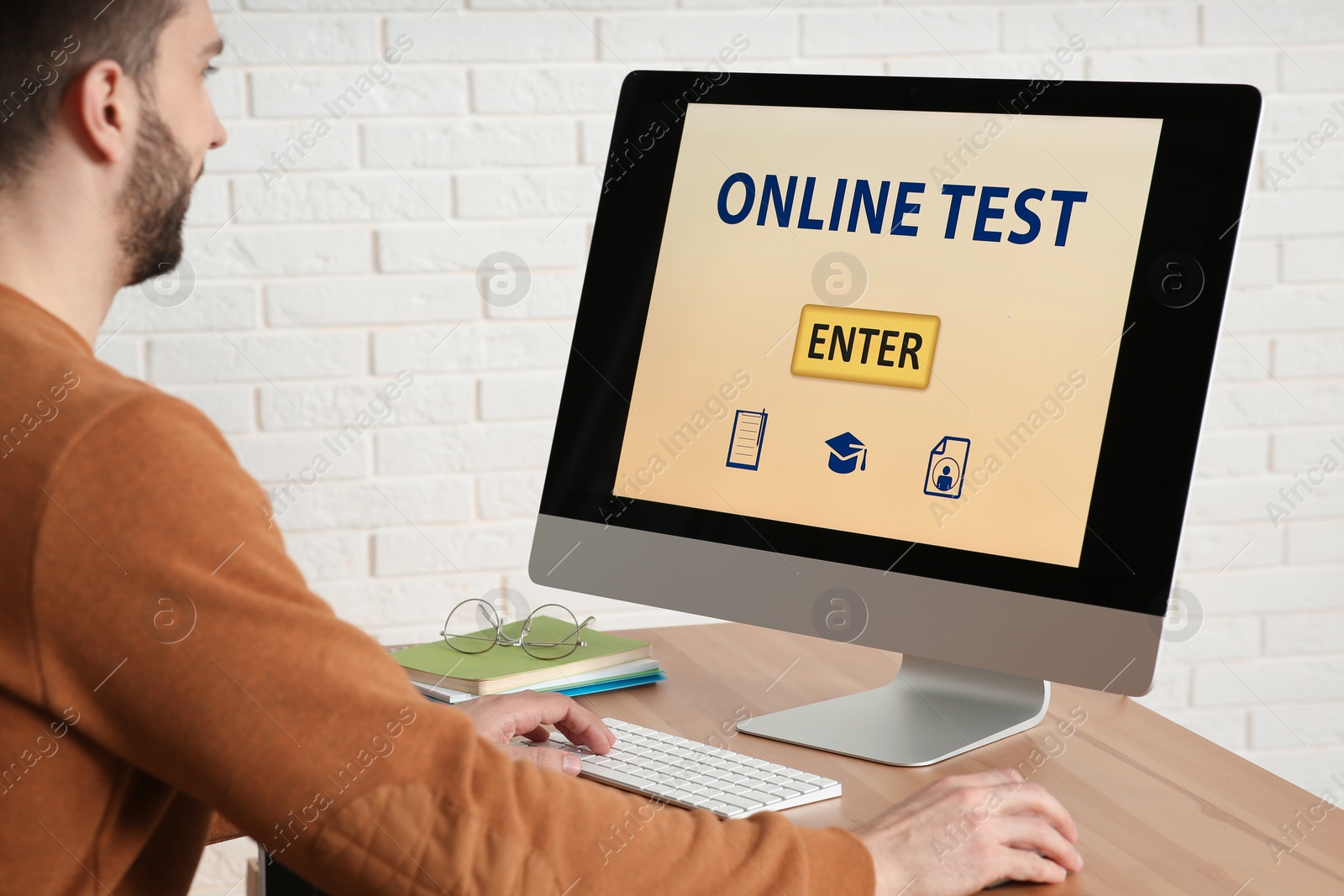 Photo of Man taking online test on computer at desk indoors