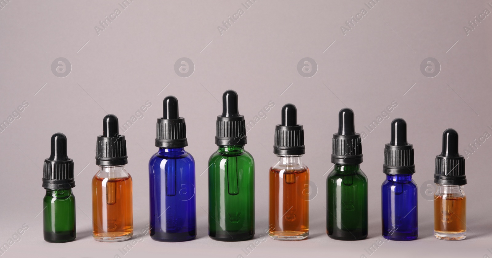 Photo of Cosmetic bottles of essential oils on color background